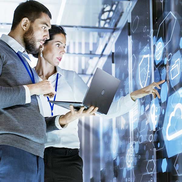 Male IT Specialist Holds Laptop and Discusses Work with Female Server Technician. They're Standing in Data Center